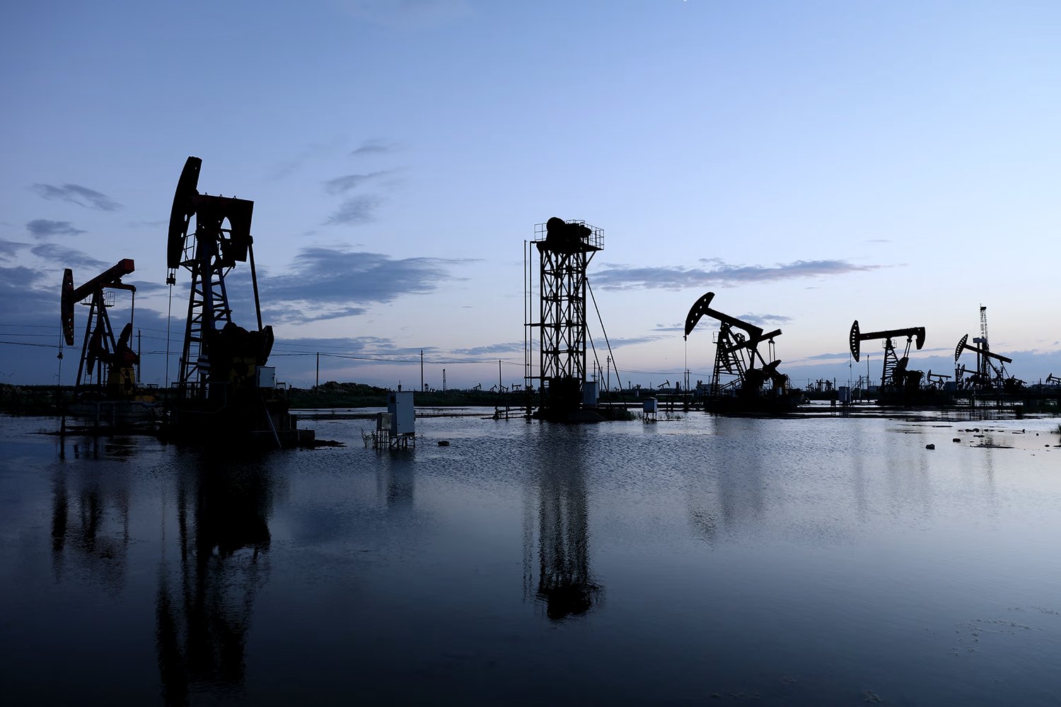 Balancines de extracción y torre de perforación en un yacimiento al atardecer